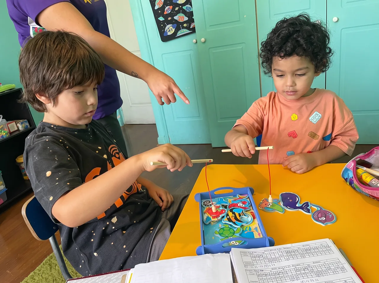 Terapeuta guiando una actividad de pesca magnética con dos niños